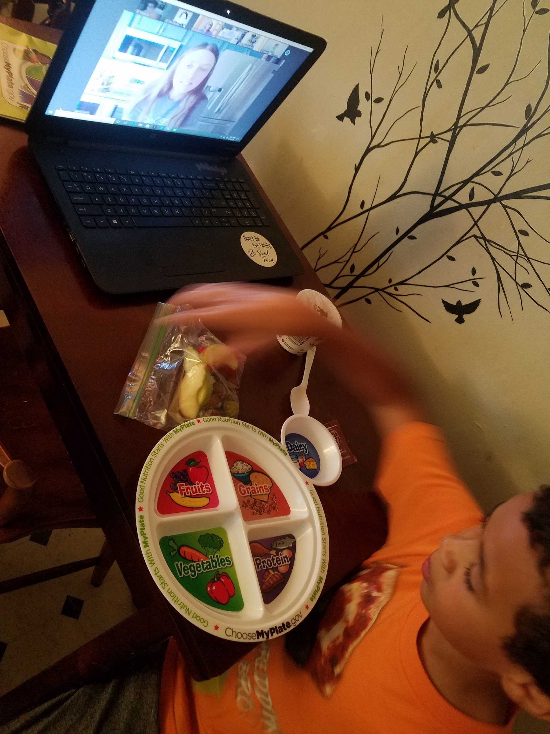 a child participates in a zoom call with a plastic MyPlate in front of him