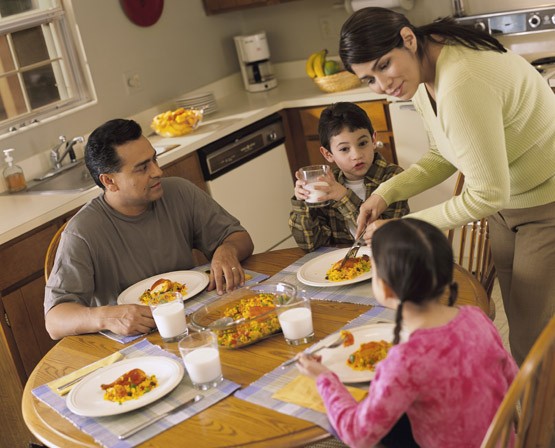 A Latino family of four sitting around a table kitchen table for dinner.