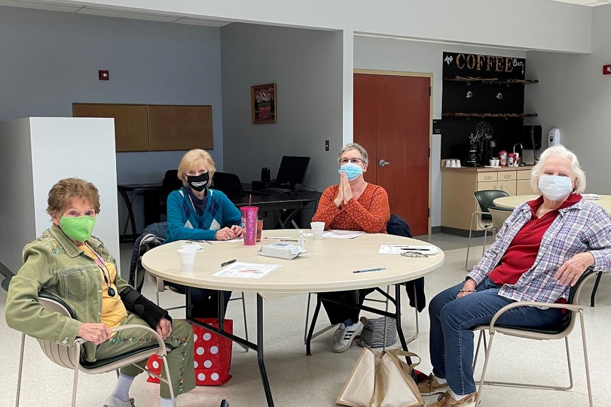 A group of senior adults sitting around a table wearing masks