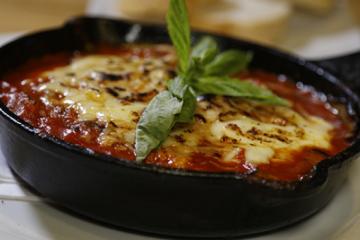 lasagna in a cast iron skillet topped with basil