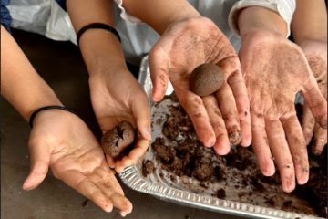 Students proudly show their finished seed balls and soiled hands