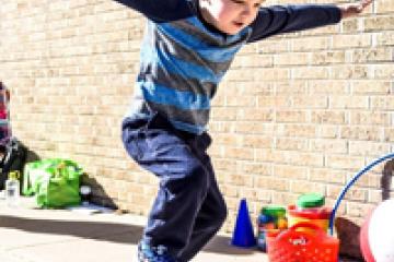 Photo of preschooler jumping with a hoolahoop.