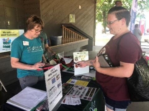 customer interacts with an educator at the farmers market