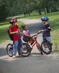 Three children taking a break during a bike ride on a paved path.