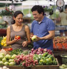 A man and woman look at produce at a farmers' market