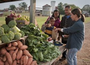 A family purchases produce from a farmers' market vendor