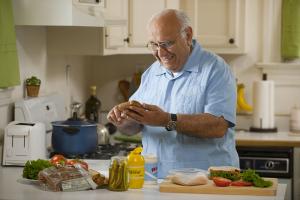 An older adult man prepares a sandwich