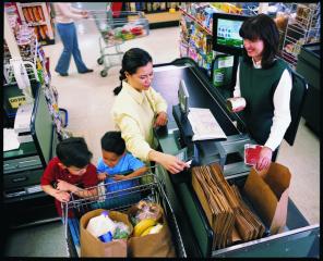 A woman with two children checking out at a grocery store and paying with a credit/debit/EBT card.